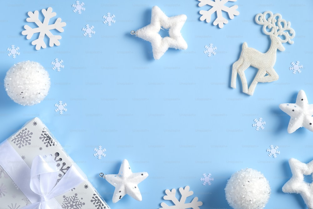 Composición de suelo plano navideño. Marco de adornos blancos, estrellas, renos, copos de nieve, bolas, caja de regalo. Navidad, Año Nuevo, concepto de vacaciones de invierno.