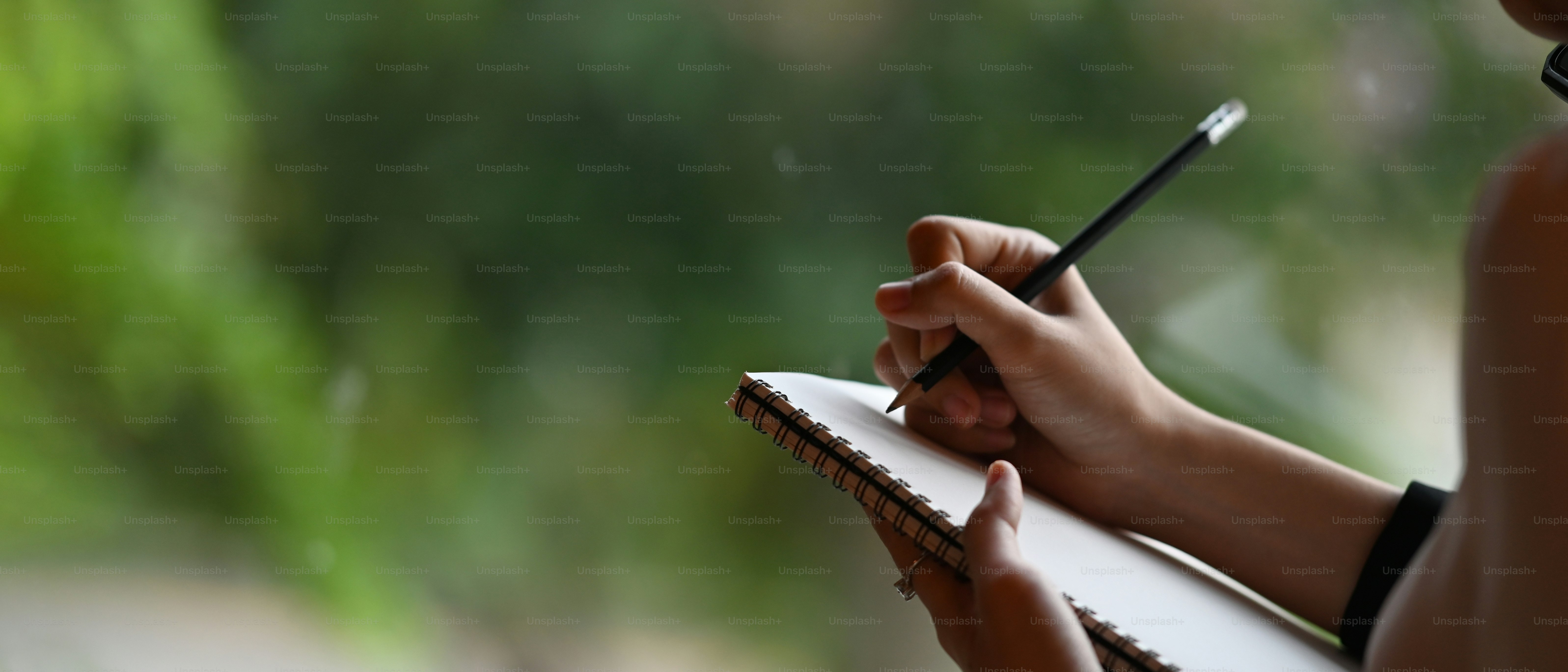 Cropped image of a businesswoman's hand is taking notes while standing over the office glass wall.