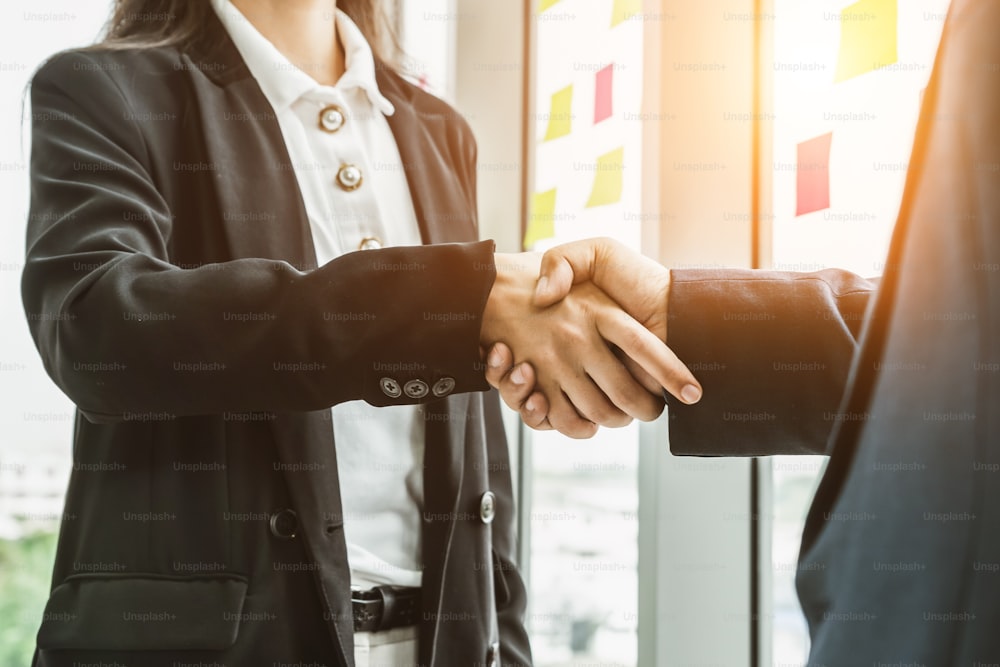 Business people handshake in corporate office showing professional agreement on a financial deal contract.