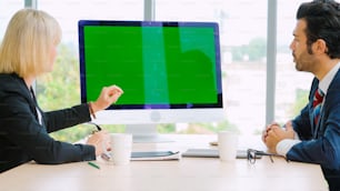 Business people in the conference room with green screen chroma key TV or computer on the office table. Diverse group of businessman and businesswoman in meeting on video conference call .