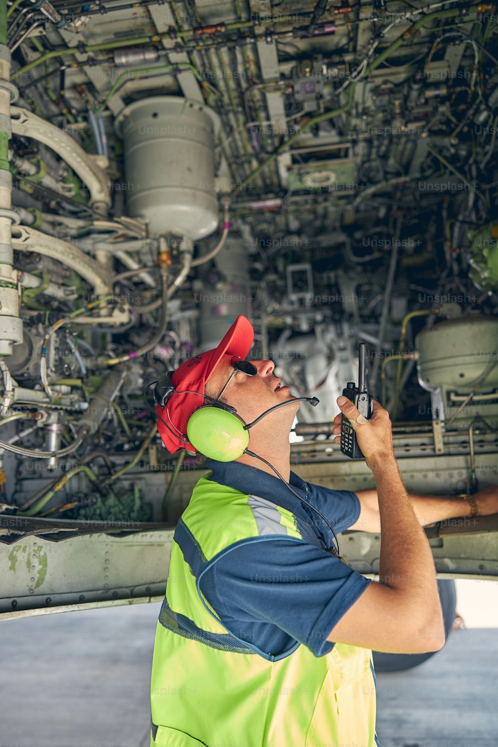 Side view of a focused maintenance technician looking up at the underbelly of the airplane