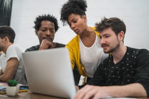 Group of multiethnic creative business people working on a project. Business woman pointing at the monitor screen and showing something to her colleagues. Business concept.