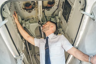 Ángulo bajo de un aviador concentrado realizando una inspección visual de un vehículo aéreo