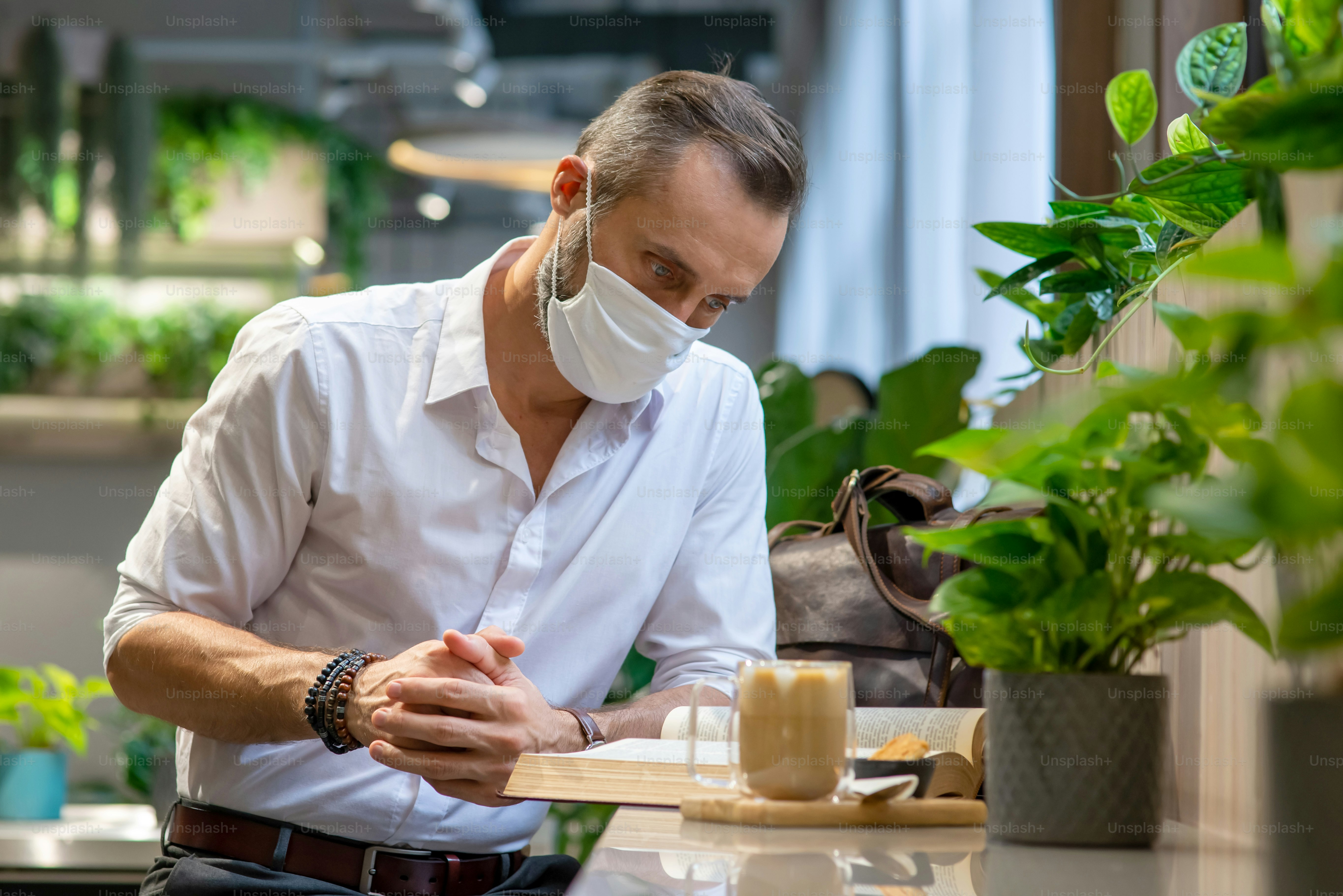 Portrait of Confidence Caucasian man wearing face mask enjoy reading a book in coffee shop.