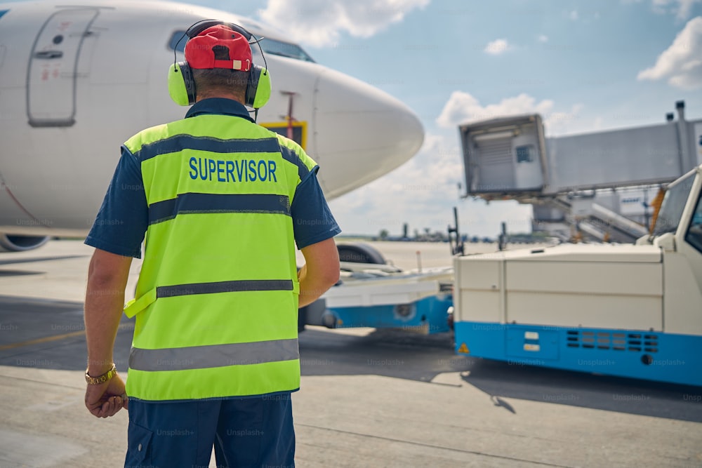 Back view of a supervisor in a reflective waistcoat standing in front of the air vehicle