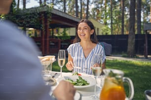 Close up portrait of laughing lady sitting at the dining table with handsome man while enjoying warm weather in the countryside