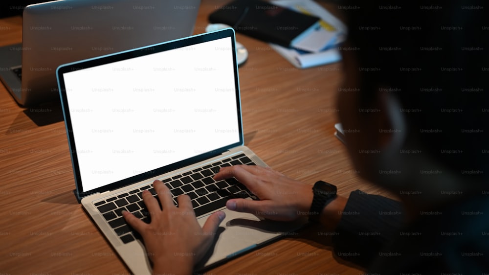 Cropped shot businessman typing mockup laptop with empty screen.