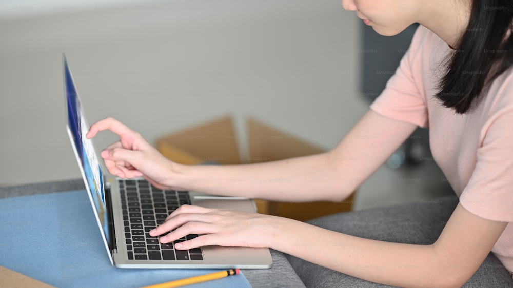 Nahaufnahme Fraucheckt ihren Computer-Laptop über einem gemütlichen Wohnzimmer. Online-Shopping, KMU-Konzept