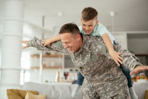 집에서 아들과 즐거운 시간을 보내는 군인. 아버지와 아들이 거실에서 놀고 있다.