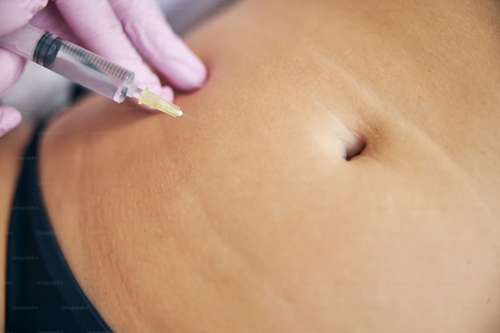 Cropped photo of a doctor injecting the contents of the syringe into the subcutaneous tissue