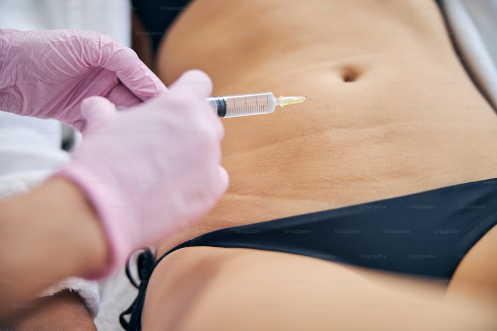Close up of doctor hands giving a subcutaneous shot to a woman with a disposable syringe