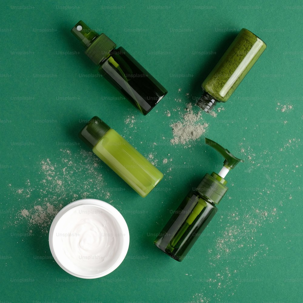 Natural moisturizer cream and green cosmetic bottles on green background. Bio organic products, skincare concept.