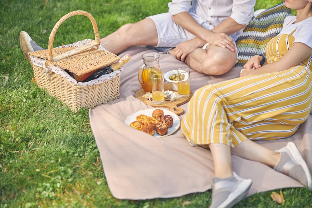 Cropped head of too young people spending time together in the garden with tasty meal and cold drink