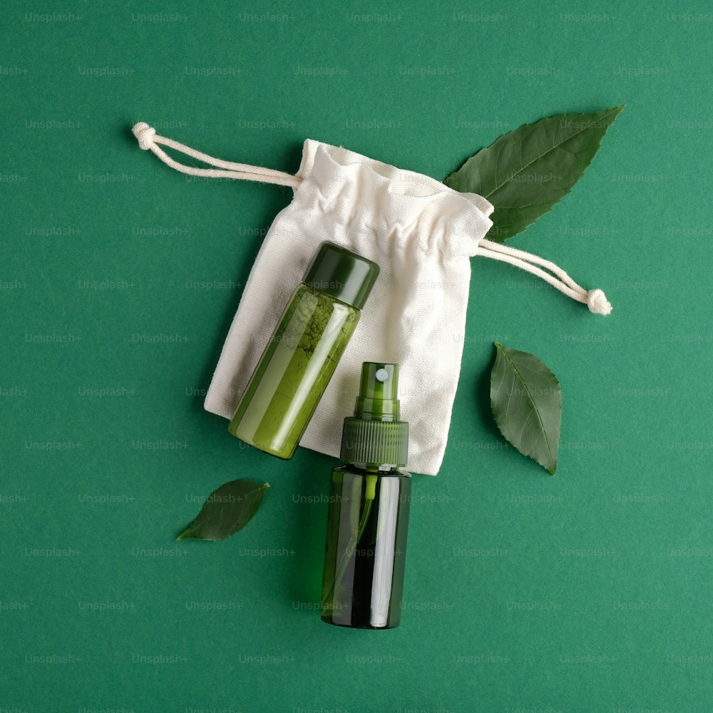 제로 웨이스트 미용 제품 세트. 녹색 화장품 병, 흰색 케이스 및 녹색 배경에 녹색 나뭇잎. 바이오 유기농 제품, 아름다움 및 스파 개념.