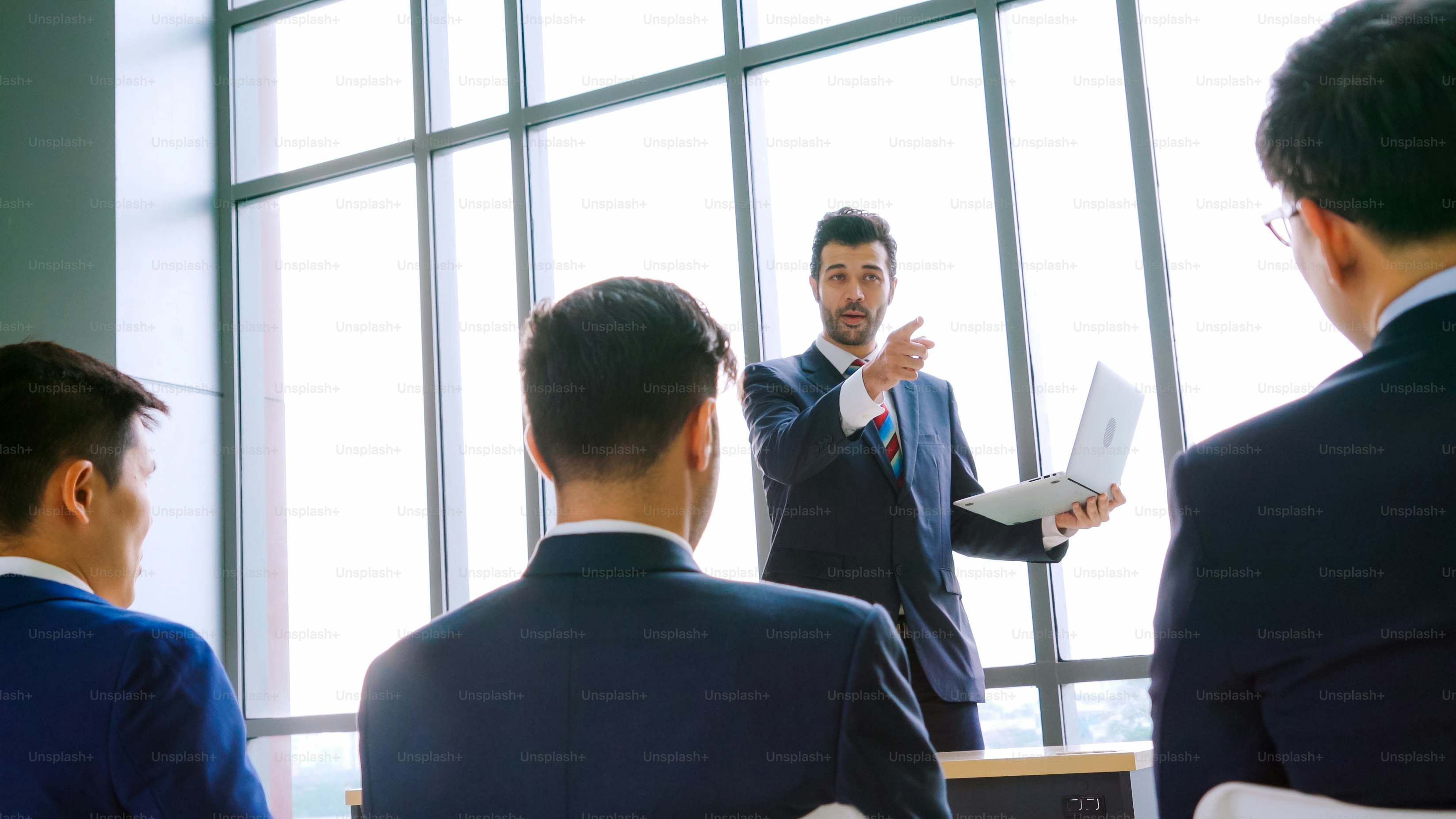 Group of business people meeting in a seminar conference . Audience listening to instructor in employee education training session . Office worker community summit forum with expert speaker .