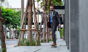 Handsome bearded man CEO in suit carrying briefcase with skateboarding to office district.