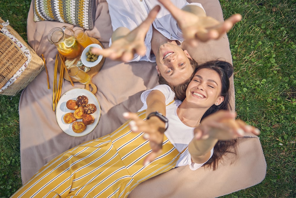 Retrato de cerca de una hermosa pareja joven que descansa a la hora del picnic con una sabrosa comida y limonada de naranja