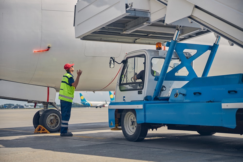 Skilled operator attaching the passenger boarding stairs to a civil plane directed by a supervisor