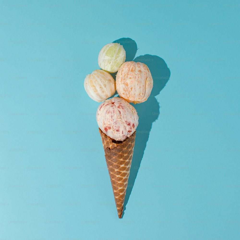 Ice cream cone with peeled citrus fruits on cyan background. Minimal summer concept.