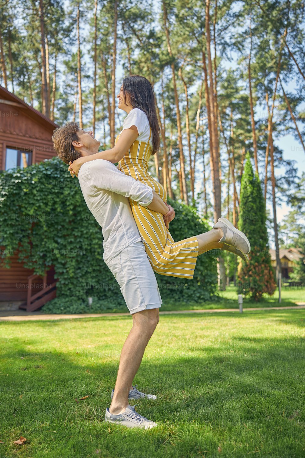 Full length portrait of strong man holding beautiful woman on hands in the outdoors