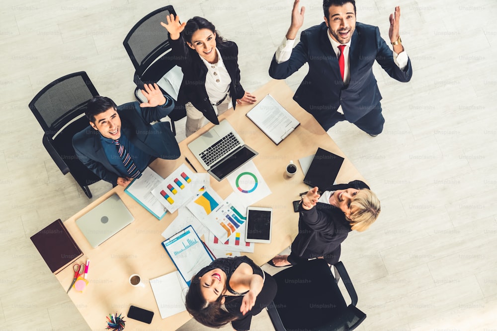 Successful business people celebrate together with joy at office table shot from top view . Young businessman and businesswoman workers express cheerful victory showing success by teamwork .