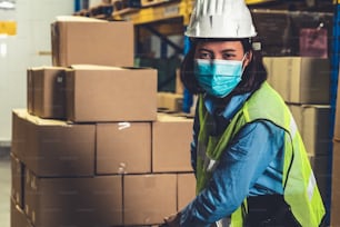 仕事再開期間中にCovid-19コロナウイルスの蔓延を防ぐためにフェイスマスクを着用して作業する工場産業の労働者。