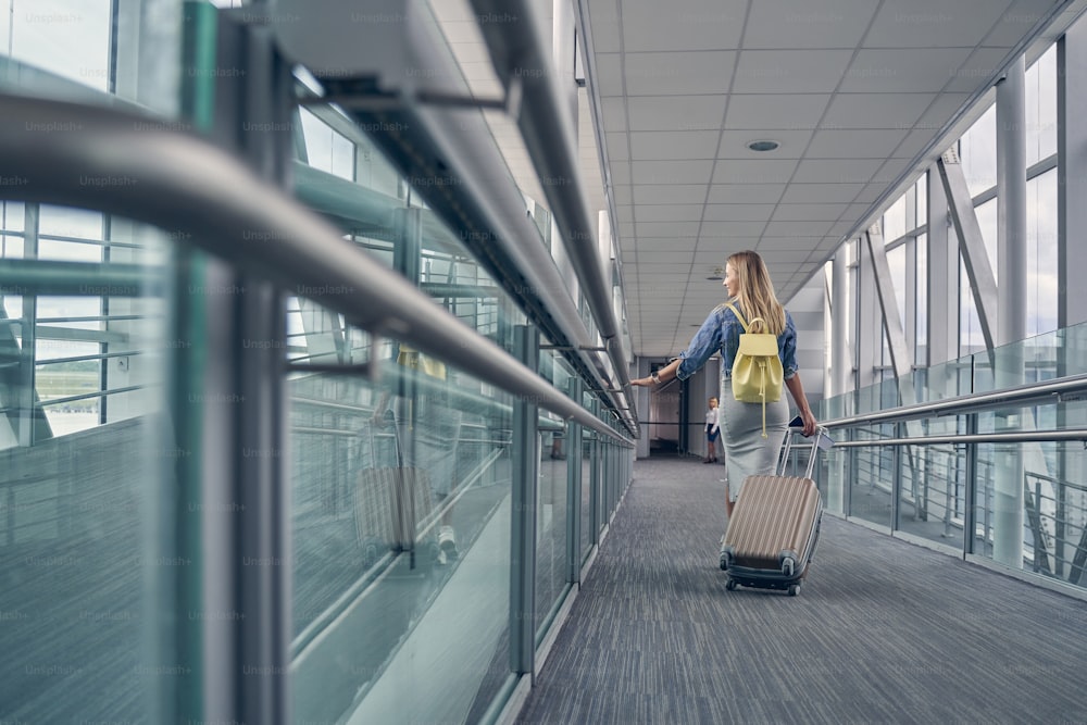 Delighted young woman turning her head while going for boarding on the aircraft