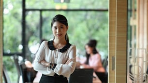 A secretary woman with crossed arm is standing in the meeting room.