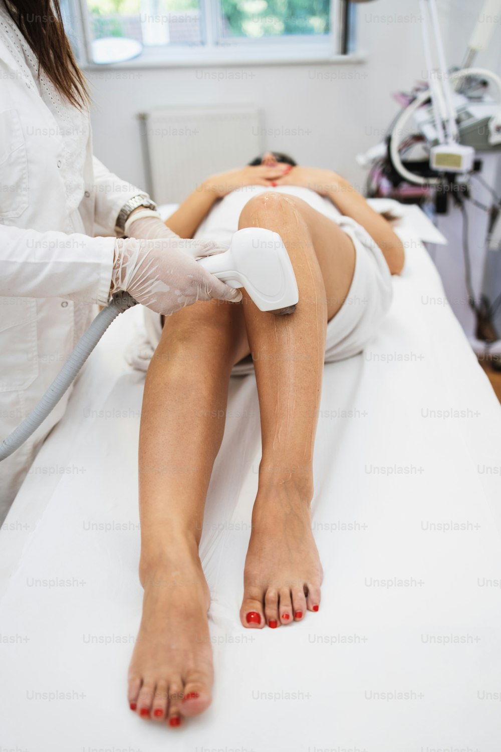 Young beautiful woman receiving legs and body skin epilation treatment. Modern body care and cosmetics concept.
