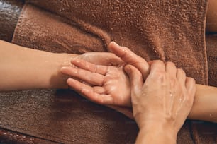 Close up portrait of women hands in the towels while massage therapist doing massage on them