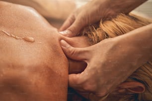Portrait de vue de dessus d’une jeune femme séduisante recevant un massage des épaules au centre de spa