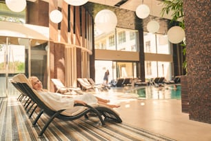 Full length of pretty woman relaxing on the deckchair by the swimming pool in spa