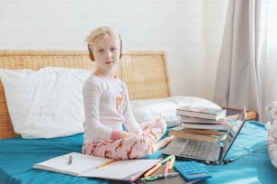 Caucasian girl child learning online on laptop Internet. Virtual class school on video call during self isolation quarantine at home. Distant remote education class. New normal and homeschooling.