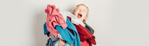 Mommy little helper. Adorable funny tired child arranging organazing clothing. Kid holding messy stack pile of clothes things. Home chores housework. Web banner header for website.