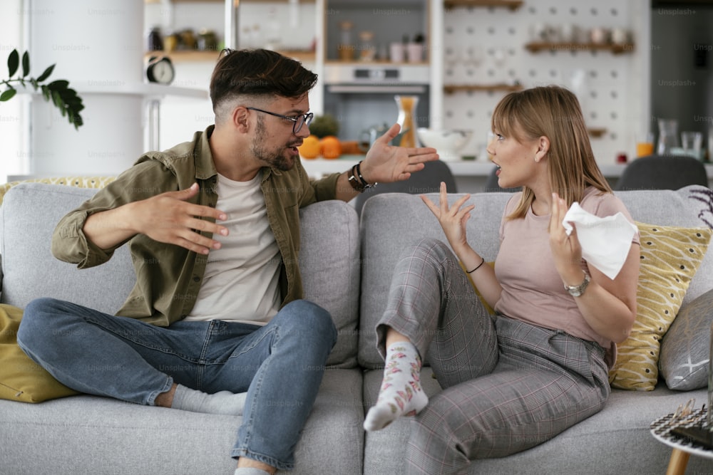 Boyfriend and girlfriend are arguing on the couch. Angry woman is yelling at her boyfriend.