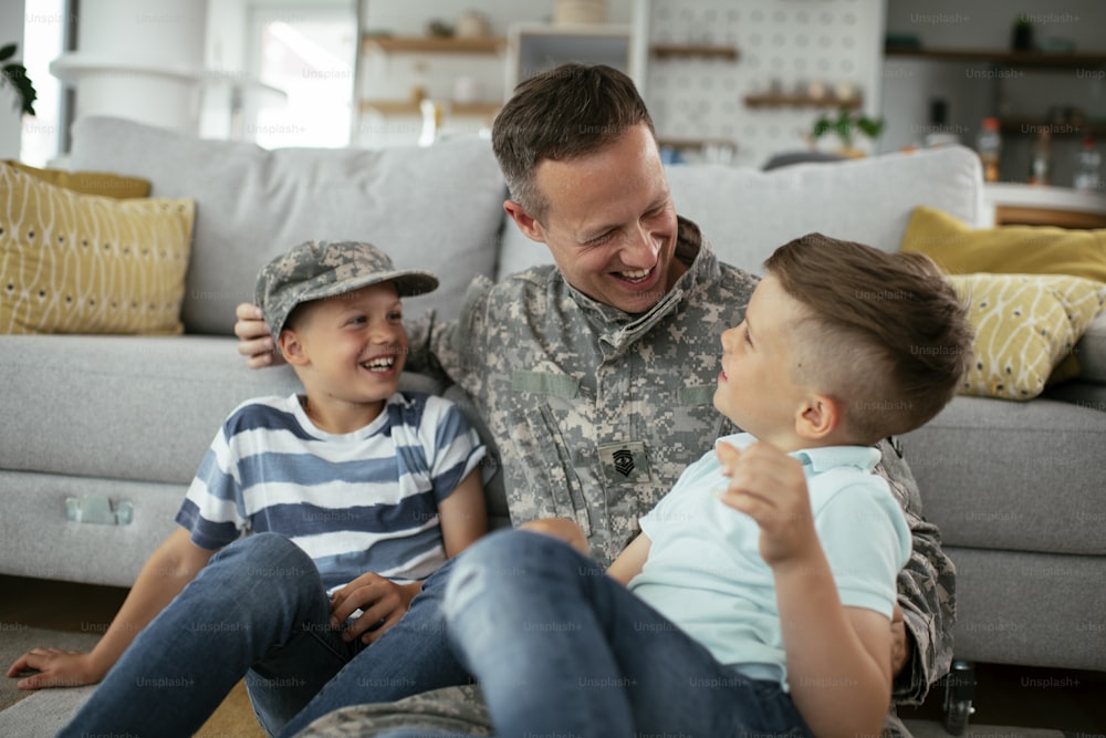 Happy soldier sitting on the floor with his family. Soldier enjoying at home with children.