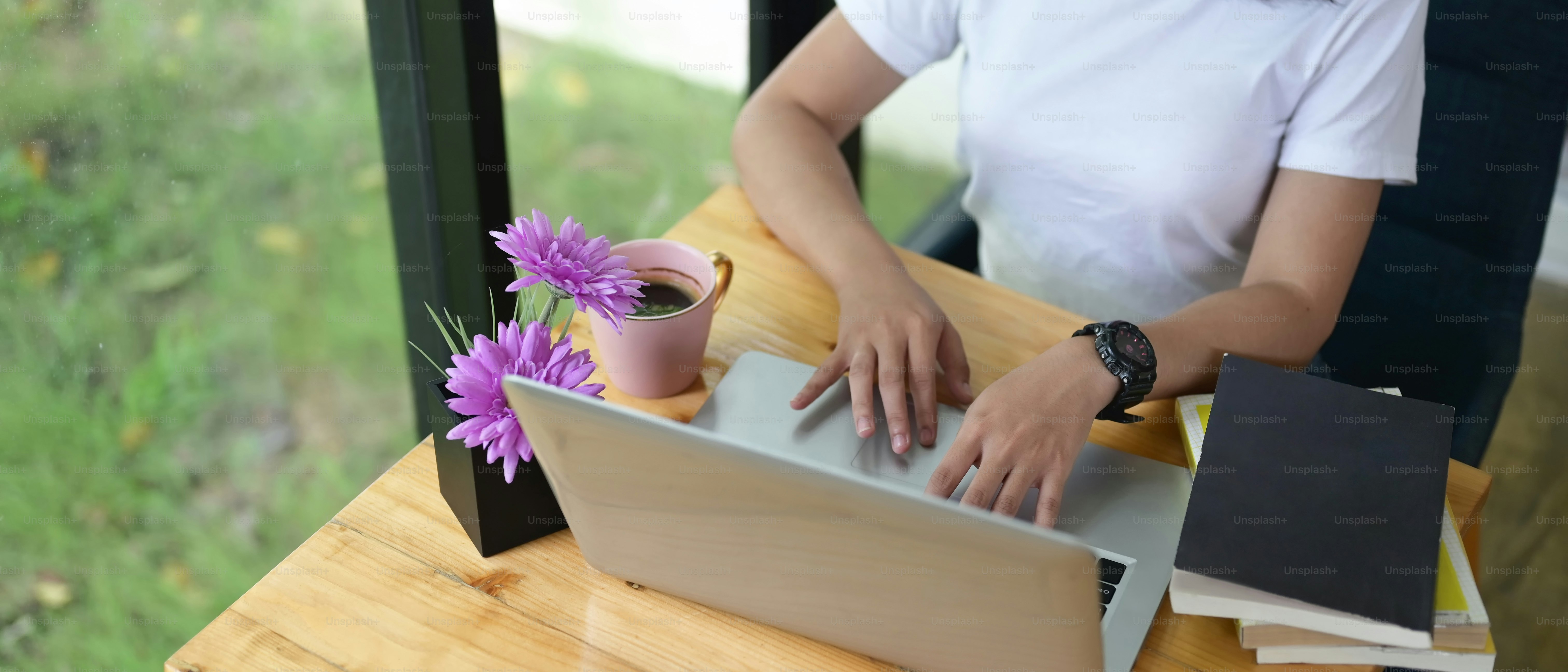 Cropped image of the woman is typing on a computer laptop at the wooden working desk.