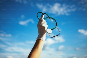 coronavirus pandemic. Closeup on medical practitioner woman with stethoscope and rubber gloves outside against sky.