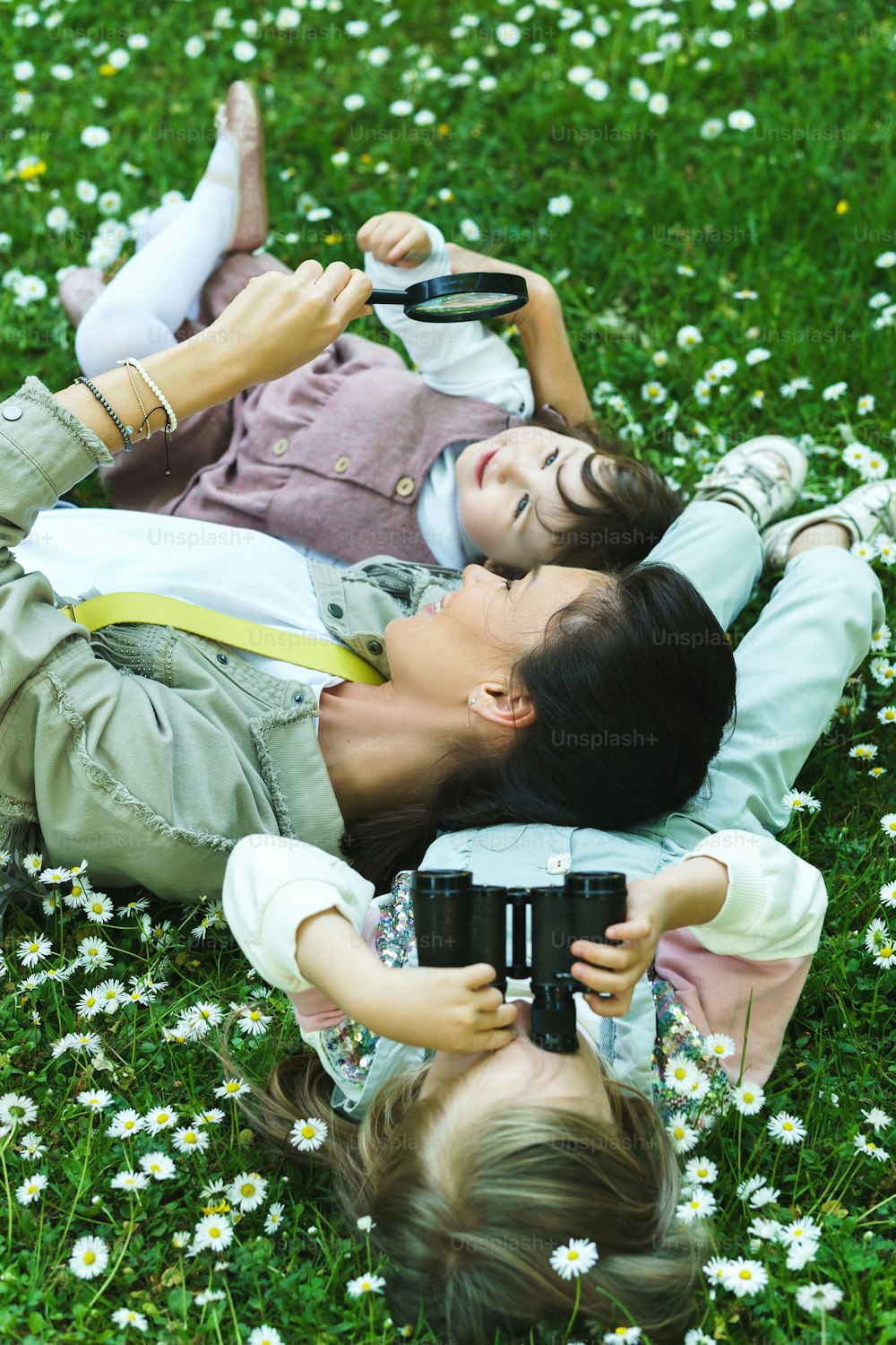 Happy family in a park. Mother and her two daughter lying in chamomile field.