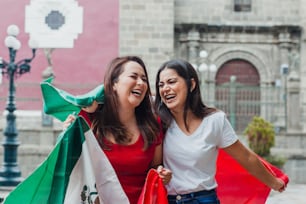 Amigas mexicanas en el día de la independencia en México sosteniendo una bandera de México