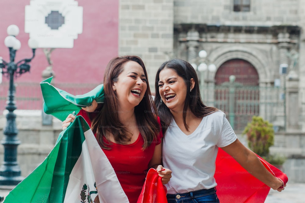 mexikanische Freundinnen beim Unabhängigkeitstag in Mexiko mit einer Flagge Mexikos