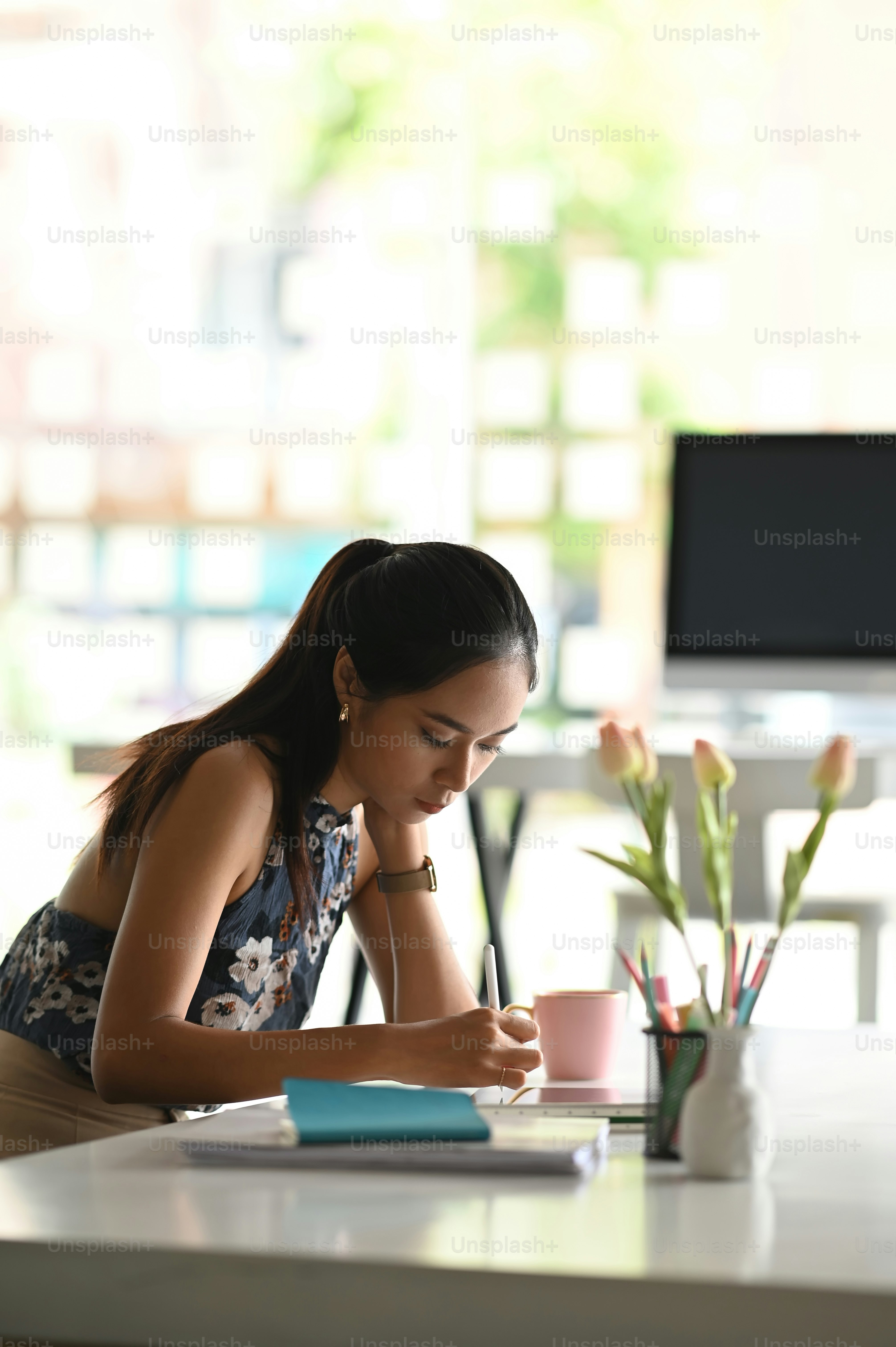 Asiatische Designerin arbeitet mit ihrem Tablet an einem modernen Arbeitsplatz.