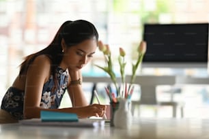 Diseñadora asiática trabajando con su tableta en un lugar de trabajo moderno.