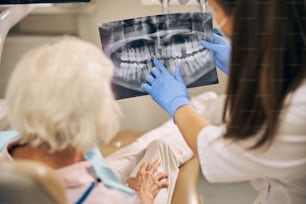 Dentista que muestra qué dientes deben repararse del paciente en el consultorio del dentista