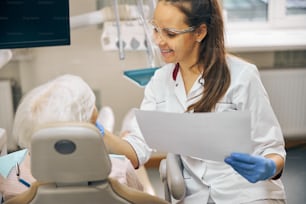 Close up portrait of smiling woman doctor sitting near the patient and examination new porcelain teeth