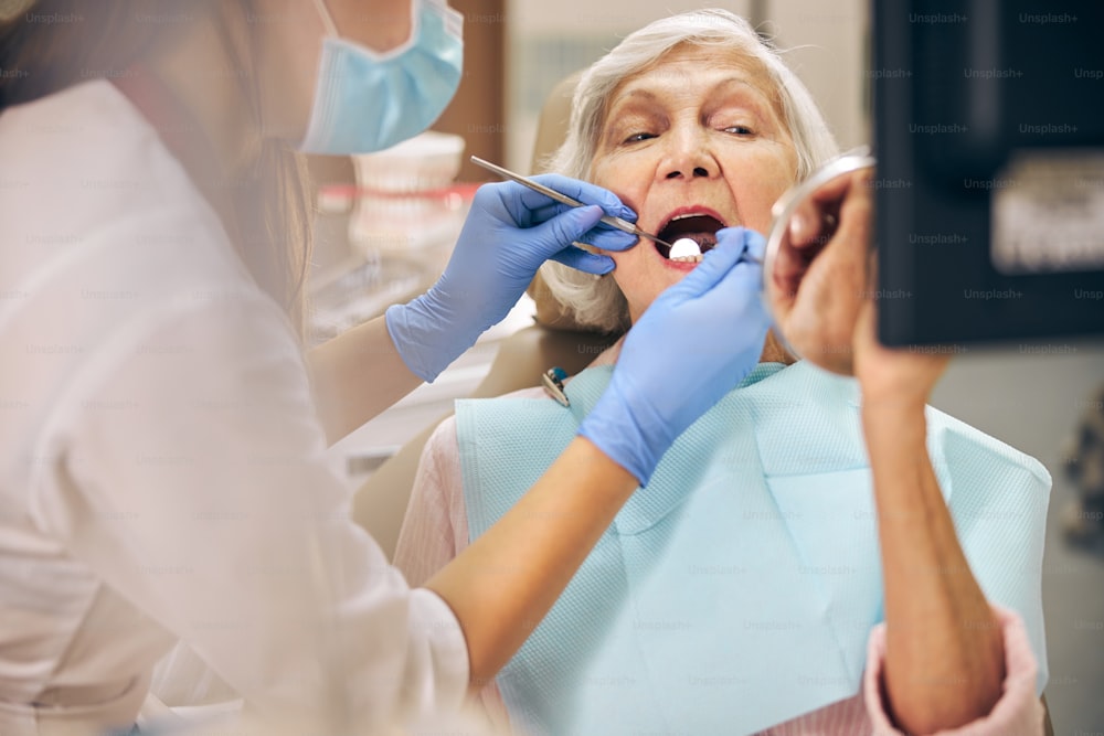 Close up of lady with open mouth during oral checkup at the dentist office