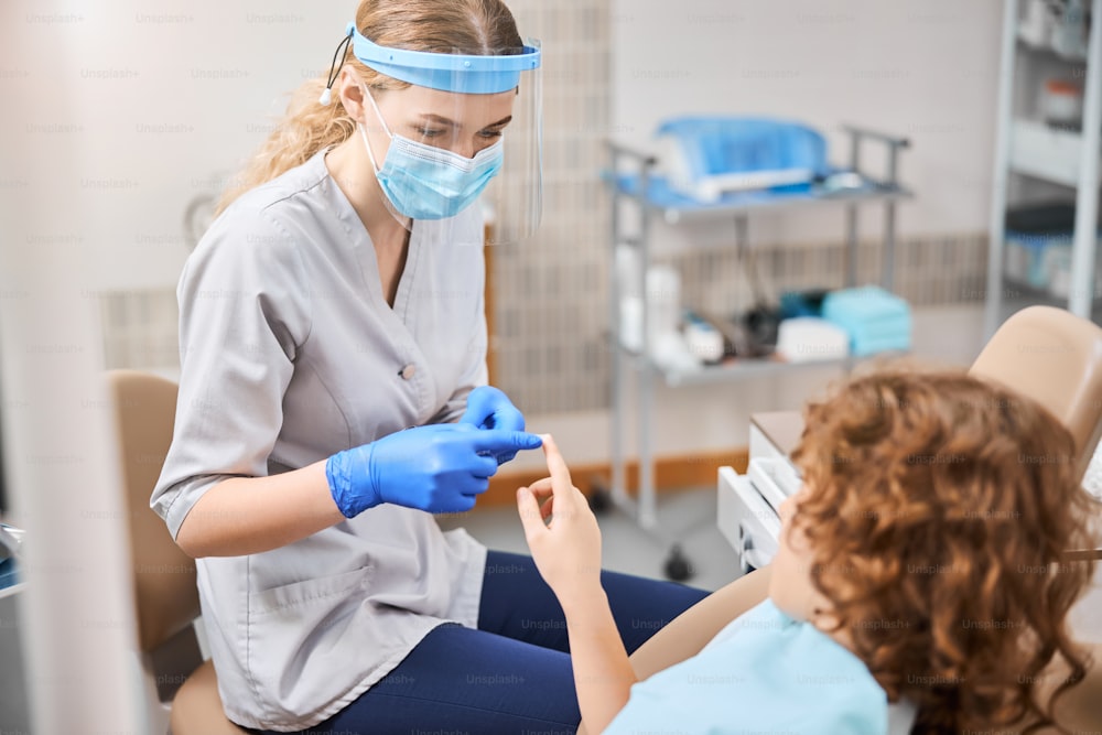 Dentista pediátrico sensato e uma criança em cadeira odontológica estão tocando os dedos na clínica