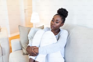 Personas, emociones, estrés y concepto de atención médica - mujer joven afroamericana infeliz que se toca la cabeza y sufre de dolor de cabeza