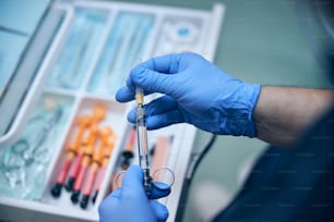 Top view close up cropped head of man hands in sterile gloves using syringe and medicine in office