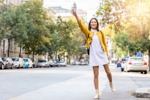 Young woman hailing a taxi ride. Beautiful charming woman hailing a taxi cab in the street. Businesswoman trying to hail a cab in the city. Tourist woman hailing a taxi